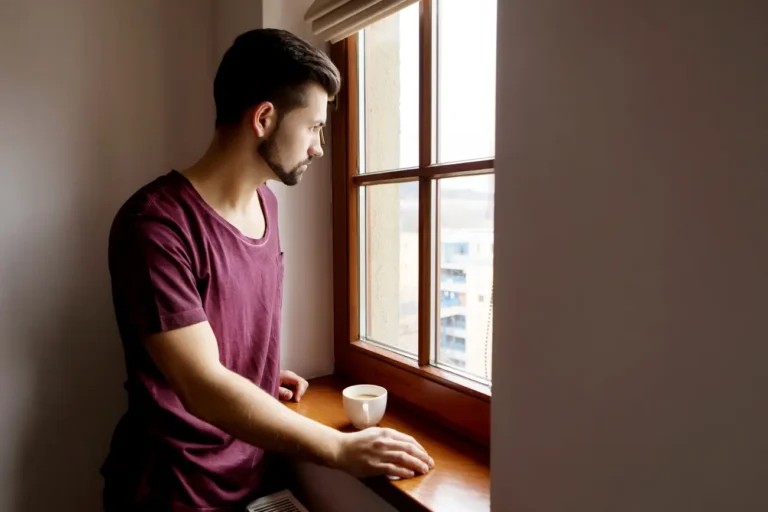 thoughtful man looking through window home